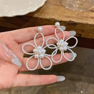 Vista dettagliata degli eleganti orecchini a perno a forma di fiore di perle in mano.