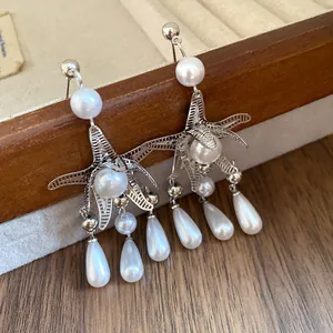 Primo piano dettagliato di orecchini a stella marina argentati con perle e gocce eleganti.