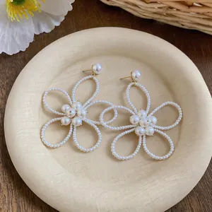 Primo piano di eleganti orecchini a bottone a forma di fiore di perle su vassoio beige