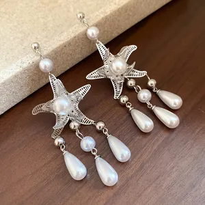 Dettaglio orecchini a stella marina in argento con eleganti nappe di perle a goccia