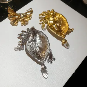 Detailed back view of vintage-style metal heart and butterfly brooches with charms