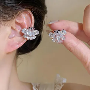 Dettaglio ravvicinato di un dolce ear cuff a forma di orsetto in zircone e resina.
