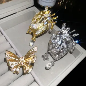 Detailed view of sparkling vintage heart and butterfly crystal brooches in a gray jewelry box
