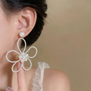 Primo piano di eleganti orecchini a perla a forma di fiore in stile francese su una modella.
