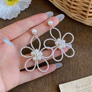 Vista dettagliata di eleganti orecchini a fiore con perline stile francese su una mano