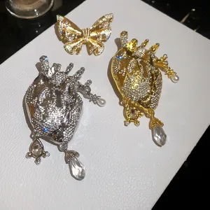 Macro detail of vintage crystal-encrusted anatomical heart and butterfly fashion brooches