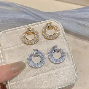 Close-up of luxury 18k gold and silver plated circular earrings with sparkly zircons.