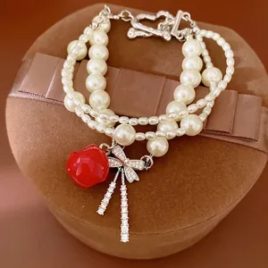 Elegante bracciale di perle multistrato con ciondolo a mela rossa e fiocco zirconi