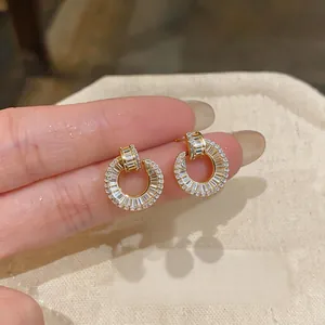 Detailed view of 18k gold-plated circular stud earrings with sparkling baguette stones