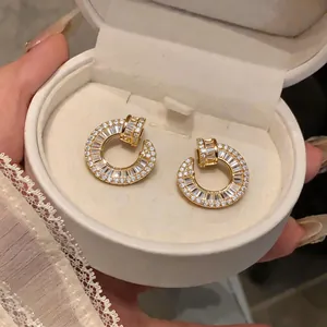 Close-up of 18k gold-plated stud earrings featuring a nail design set with zircons