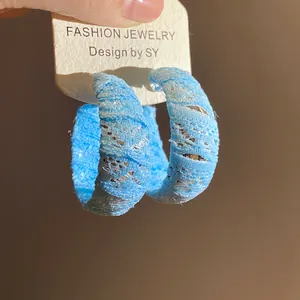 Primo piano di orecchini a cerchio a C avvolti in pizzo di chiffon blu chiaro da donna