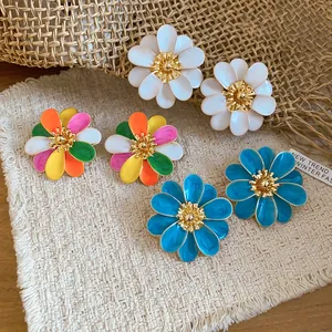 Close-up of colorful enamel flower stud earrings in white, blue, and mixed petals.