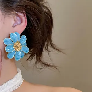 Close-up of blue enamel flower stud earring worn on model for a stylish look