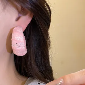 Dettaglio di un orecchino a forma di C in chiffon rosa con sottili riflessi argentati