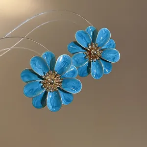 Detailed macro shot of elegant blue enamel flower stud earrings with gold-tone stamen centers.