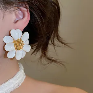 Elegant white oil-dripped flower stud earrings shown on ear in a close-up detail shot