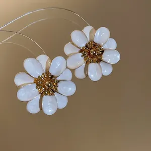 Close-up detail of elegant white and gold oil-dripped flower stud earrings for women