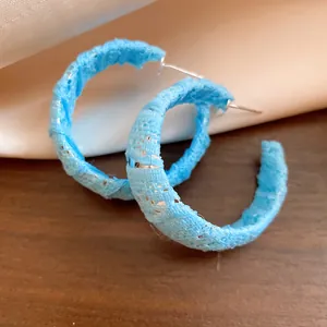 Primo piano di orecchini a cerchio a C avvolti in chiffon azzurro con aghi d'argento