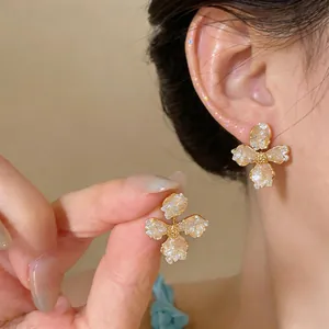 Close-up of elegant flower stud earrings with textured glass petals and golden centers.