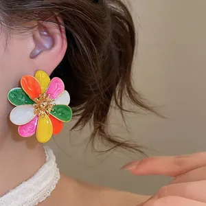 Close-up view of a large colorful enamel flower earring worn on an elegant model's ear