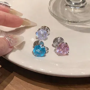 Macro detail of colorful faceted zircon round clip-on earrings in pink, purple, and blue