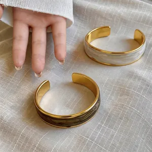 Eleganti bracciali a polsino dorati con inserto in smalto marmorizzato ondulato moda