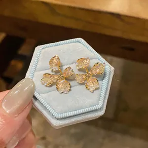 Close-up view of elegant flower stud earrings with crushed glass petals on a blue velvet box