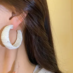 Primo piano di un elegante orecchino a cerchio a C avvolto in chiffon bianco su orecchio