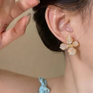 Close-up detail of a minimalist flower stud earring with shimmering glass petals.