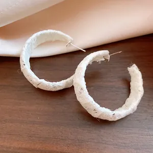 Dettaglio ravvicinato di orecchini a cerchio a C avvolti in chiffon bianco