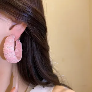 Primo piano di orecchini a cerchio a C avvolti in chiffon rosa con dettagli glitter