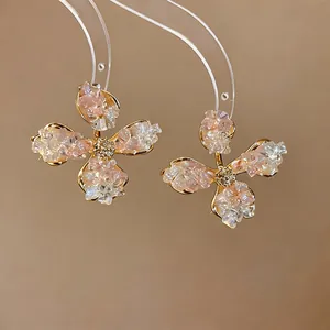 Macro detail of elegant pink crushed stone flower earrings with golden trim on a clear stand.