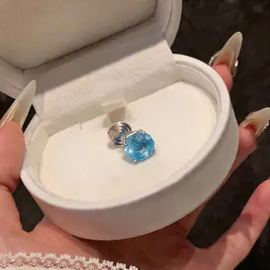Macro view of a light blue round zircon clip-on earring presented in a white gift box