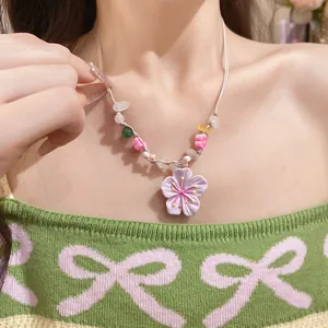 Macro view of 3D purple cherry blossom pendant and colorful beaded necklace detail