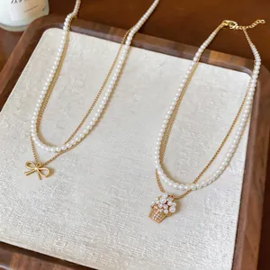 Dettaglio di collane di perle con ciondoli a fiocco e cesto di fiori in zircone.