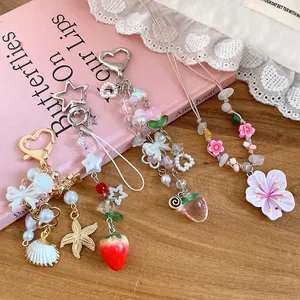 Detailed view of floral beaded necklaces and charms with strawberry and shell accents