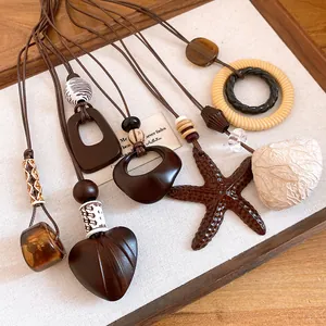Close-up detail of vintage heart and starfish pendants on long leather sweater chains