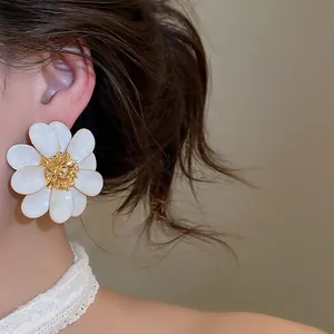 Detail of elegant white flower earrings with gold center on a model.
