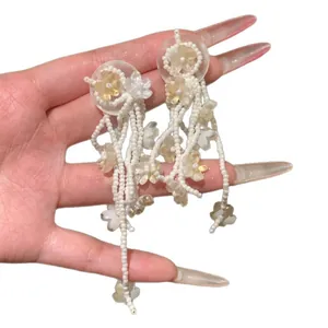 Floral beaded tassel earrings with white and yellow petals for a sweet vacation style.