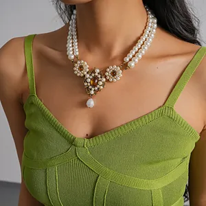 Detail of vintage double-layer resin pearl necklace with amber-colored flower pendants.