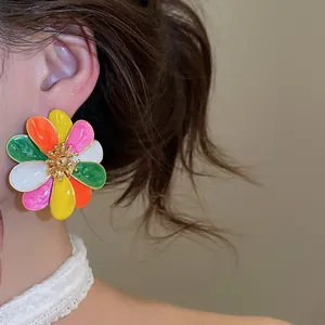 Detailed view of multi-color enamel flower stud earrings worn on a model's ear for fashion