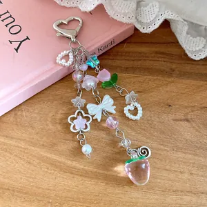 Detailed close-up view of pink strawberry charm and white bow on sweet beaded accessory