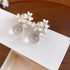 Detail view of French resin flower earrings with sparkling crystal centers and grey drops