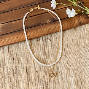 Elegante collana a due strati di perle con un ciondolo a fiocco in zircone brillante in dettaglio