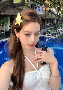 Asiatisches Model mit einer gelben Seestern-Haarklammer mit Perle in einem Resort am Pool