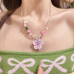 Macro view of a 3D purple cherry blossom beaded necklace worn by a female model.