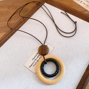 Detailed view of the layered resin and wood ring pendant on a vintage cord necklace