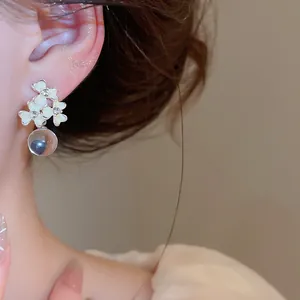 Close-up of French resin flower earrings with sparkling rhinestones and drop pearls