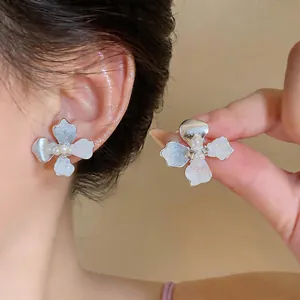 Detailed close-up showing elegant silver flower stud earrings with central pearl accents