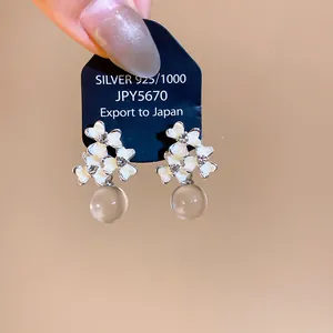 Detail of French flower earrings with white enamel petals and clear resin beads